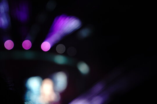 Abstract colorful concert bokeh background with blurred stage lights and glowing pink light stick silhouette, creating an energetic nightlife and live music atmosphere with soft defocused illumination