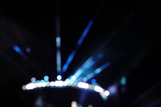 Abstract colorful concert bokeh background with blurred stage lights and glowing pink light stick silhouette, creating an energetic nightlife and live music atmosphere with soft defocused illumination