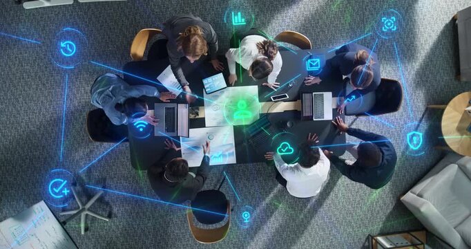 Top Down View of Diverse Business Team Gathered Around Meeting Table With Laptops and Statistical Reports. Visualization Icons Represent Connectivity, Cloud Security. Action Zoom out camera.