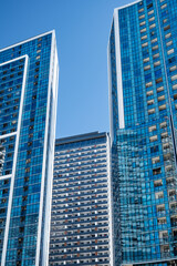 Obraz premium Modern high-rise residential buildings with glass facades against a clear blue sky.