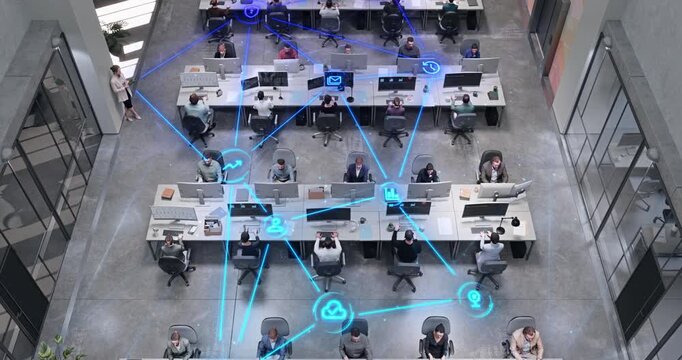 Top Down View Open Plan Office With Diverse Employees Working at Computer Desks as Linked Visualization Layer Appears. Glowing Blue Icons Email, Cloud Sync and Analytics.