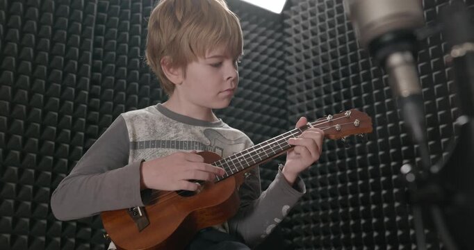 Boy Play Music on Ukulele Instrument in Home Studio. 4K 10-bit