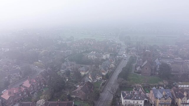 4K drone footage showing mist rolling across a suburban landscape with rooftops barely visible.