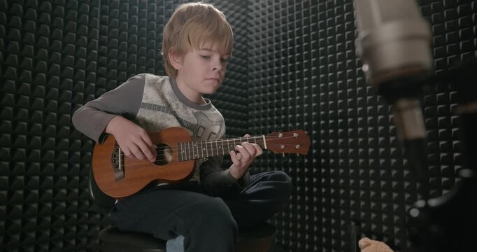 Boy Play Music on Ukulele Instrument in Home Studio. 4K 10-bit