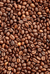 Fototapeta premium Brown roasted coffee beans in big pile on table close up. Large amount of coffee grains