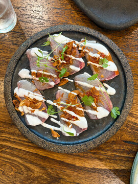 A plate of kingfish sashimi with coconut cream sauce.