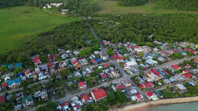 Aerial dolly of Magnesia Del Norte, Catanduanes, a coastal barangay with shoreline homes, and lush tropical greenery - Philippines