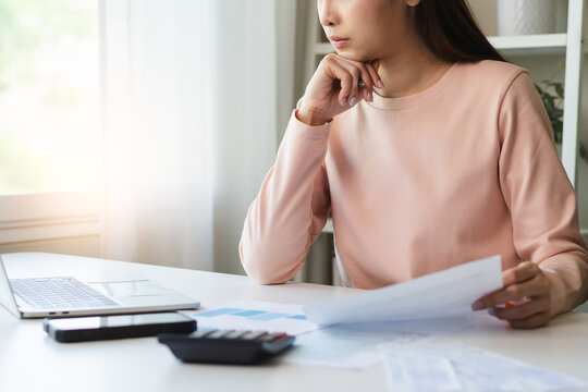 Deduction planning, debt asian young woman  hand using calculator to calculating money balance from bill and income, cost budget expenses for pay money form personal individual on table at home.