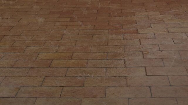 A heavy rain falling on a brick patio in slow motion