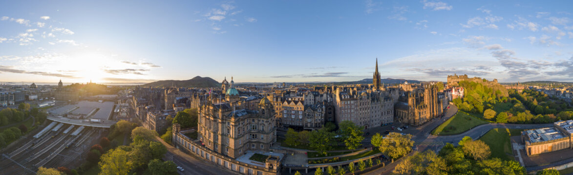 Aerial view of the historic Edinburgh skyline featuring the castle and Old Town architecture under a golden sunset sky in Edinburgh, Scotland, United Kingdom.