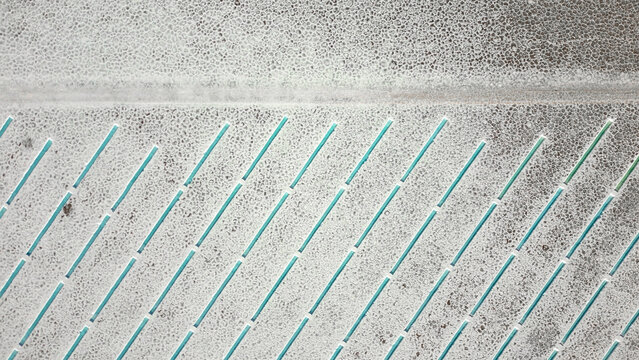 Aerial view of Salinas Grandes salt flats featuring geometric turquoise water channels and textured white salt crust in Tumbaya, Jujuy, Argentina.