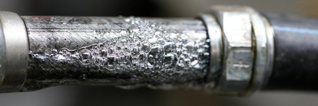 Medium shot of a specialized hose test on plumbing systems with visible bubbles forming at potential leak points under pressure in a maintenance setting.
