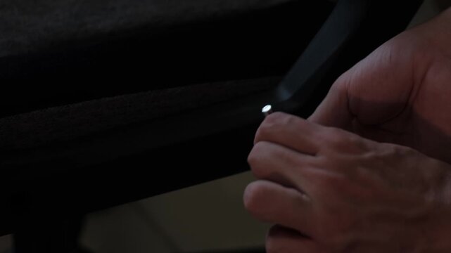 Close-up shot of hands using an allen key to secure a component beneath an office chair seat during indoor assembly