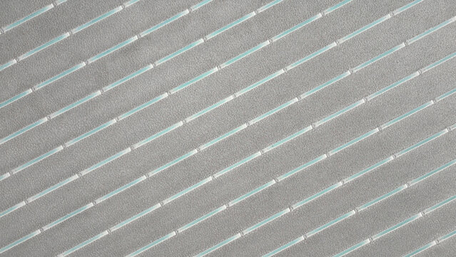 Aerial view of Salinas Grandes salt flats featuring parallel turquoise water channels and textured grey salt crust in Tumbaya, Jujuy, Argentina.