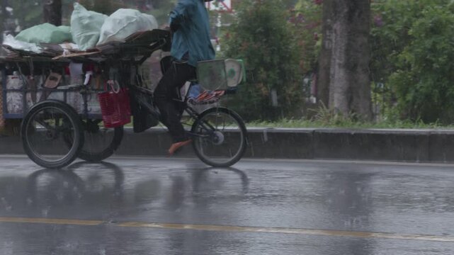 Vietnamese street recycler carrying collected plastic and waste on a bicycle in the rain