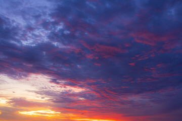 Fototapeta premium A breathtaking, vibrant sunset sky filled with dramatic, textured clouds painted in brilliant shades of fiery orange, deep magenta, and soothing twilight purple, capturing the serene beauty.