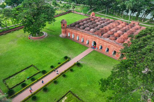 Aerial view of the Sixty Dome Mosque featuring historic red brick architecture and multiple domes surrounded by lush green lawns in Bagerhat, Khulna Division, Bangladesh.