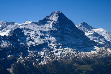 Fototapeta premium Snow Covered Alpine Mountain Peak Over Valley Landscape With Blue Sky in Spring Light