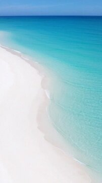 Serene turquoise water meeting pristine white sand under a clear blue sky, ideal for relaxation.