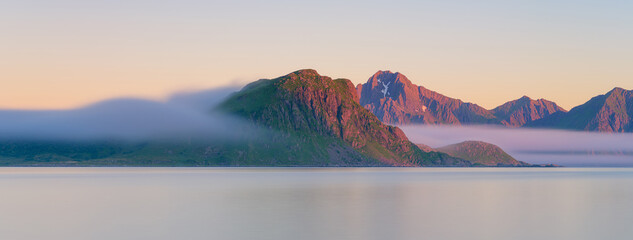 Panoramic view on the fjord during midnight sun in Lofoten islands, Norway. Long exposure. Scenic arctic summer landscape with golden hour light and northern nature. © biletskiyevgeniy
