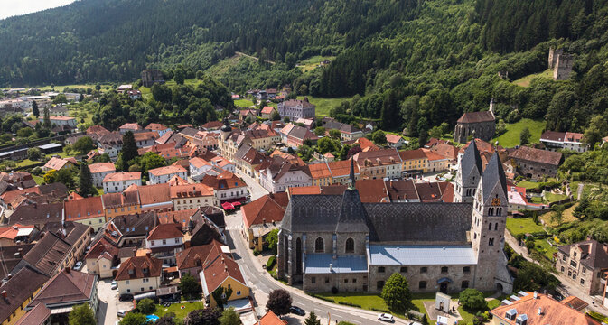 Summer drone footage showing medieval Friesach, old fortified walls, rooftops, towers, hills, serene atmosphere, warm daylight, gentle cinematic motion