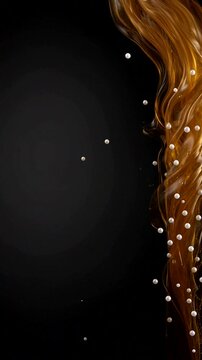 Golden liquid swirl with floating pearls on black background creates a modern and elegant abstract scene.