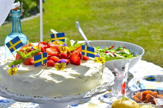 A cake decorated with strawberries, new potatoes and herring to celebrate the summer solstice on the festive table.Midsummer in Sweden.