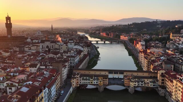 Flying above the Renaissance bridge in Florence, Italy at sunrise, Ponte Vecchio and Arno river at sunrise, drone view of Florence, Italian historic town in Tuscany