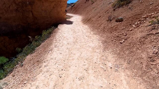 Point of view of a man hiking the navajo loop trail inside bryce canyon national park, utah, taking a selfie while admiring the incredible geological formations called hoodoos on a sunny day