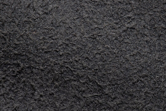 Macro shot of dark gray or black fleece textile material. Top view close up of soft warm synthetic fabric texture, detailed fiber backdrop for winter clothing and fashion design.