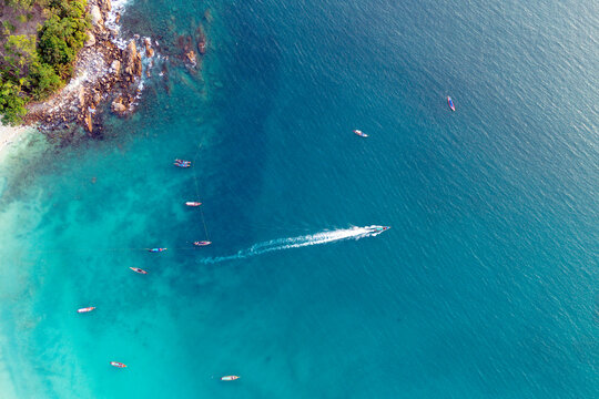 Tropical Patong beach in Phuket, Thailand, showcases clear turquoise water where longtail boats are moored