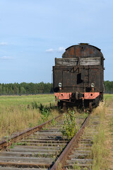 Rear view of an old rusty vintage steam locomotive on abandoned railway tracks. Retro industrial background © Olga Spasionnikova
