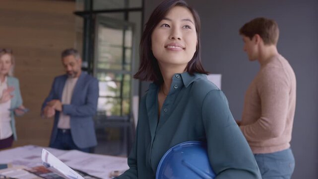 Smiling architect holding blue helmet and new project