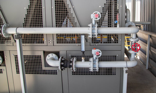Close-up of water cooling system pipes, butterfly valves, and pressure gauge in a factory.Industrial chiller system piping with valves and thermometer sensor.