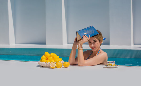 Italian summer resort, woman in blue bikini at villa Pool with lemons. Vacation season concept