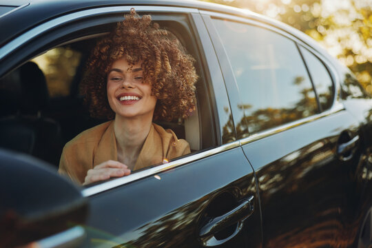 A smiling woman leans from a car window during golden hour, embracing a carefree street style. The retro film color palette adds warmth and nostalgia, capturing everyday joy in motion.