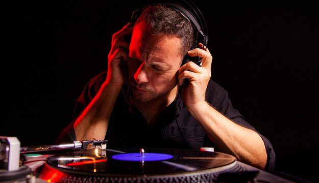 Hombre joven escuchando un disco de vinilo con los auriculares