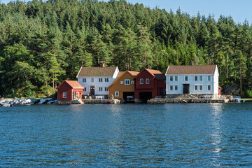 Fototapeta premium Scandinavian harbor community with colorful waterfront houses, small marina and quiet coastal village atmosphere near Lindesnes Lighthouse in Norway for tourism and Nordic living