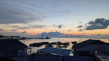 Fototapeta premium Beautiful sunset over a peaceful harbor with colorful sky reflections, calm ocean water, and dramatic clouds during twilight