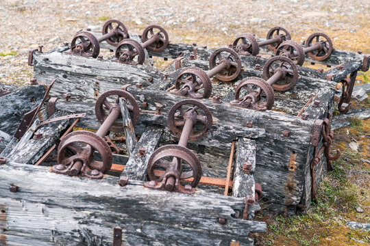 View of rusty iron wheels and weathered wooden frames of abandoned industrial equipment at Varsolbukta on the rocky tundra Svalbard, Svalbard and Jan Mayen.