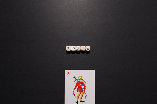 Power spelled with letter tiles above a joker card on dark background, symbolizing control, dominance, leverage and strategic advantage.