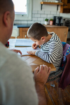 Parent helping child with homework at kitchen table