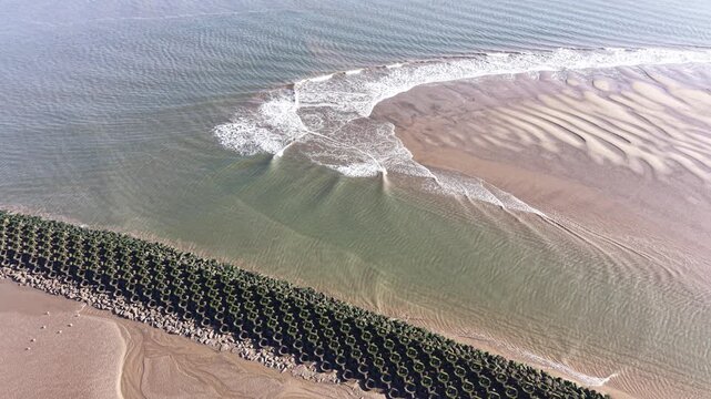 A detailed 4K video showing low tide conditions at New Brighton Beach, featuring drifting water patterns, exposed sand textures and a clear coastal horizon stretching across the Wirral shoreline.