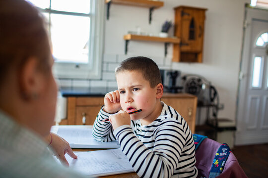 Boy studying with parent at kitchen table at home