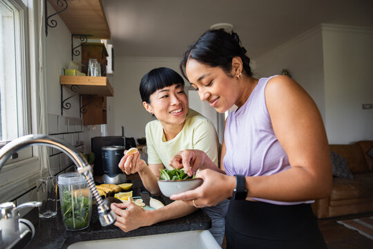 Two women preparing a healthy smoothie in a home kitchen