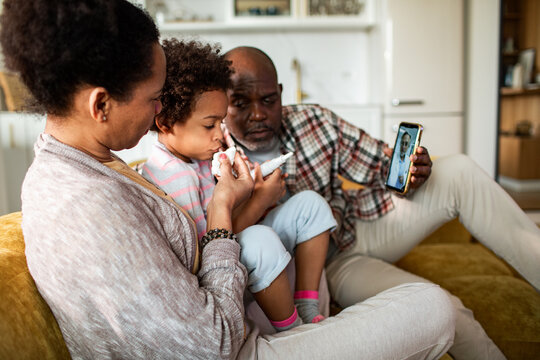 Parents help sick child during telehealth call at home