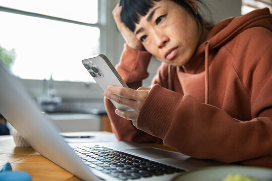 Worried woman checking smartphone while working from home