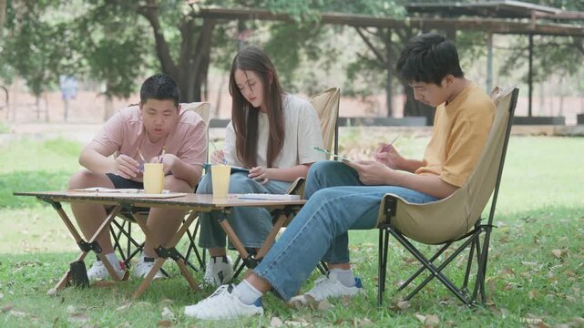 Shared Moment of Focus: Friends engaged in a study session under the open sky, notebooks open and pens poised, a picture of collaborative learning.