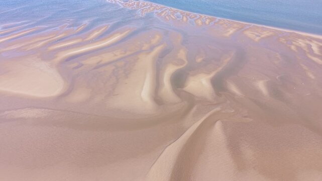 A dynamic 4K coastal video capturing the tidal zone at New Brighton Beach, showing shifting water channels, natural sand formations and bright coastal lighting conditions.