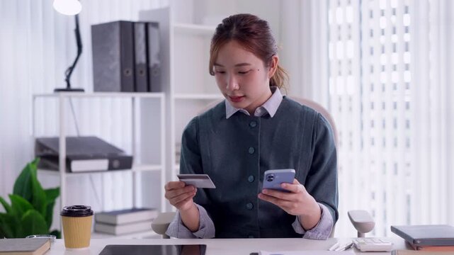 Asian businesswoman entrepreneur using credit card smartphone mobile payment online shopping banking ecommerce transaction finance managing purchase home